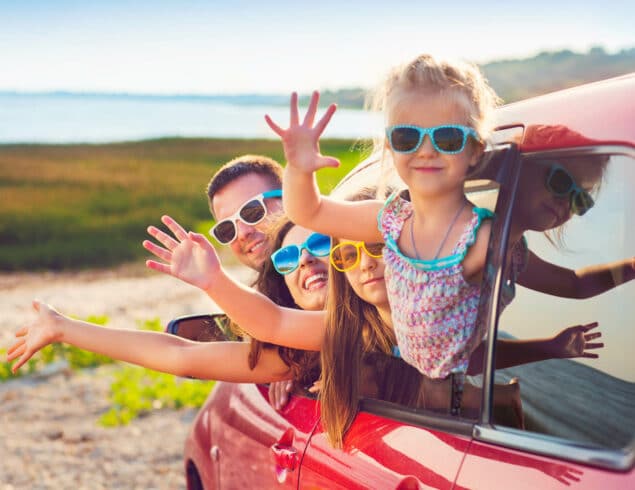 Famille saluant par la fenêtre d’une voiture