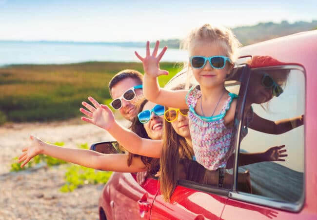 Famille saluant par la fenêtre d’une voiture