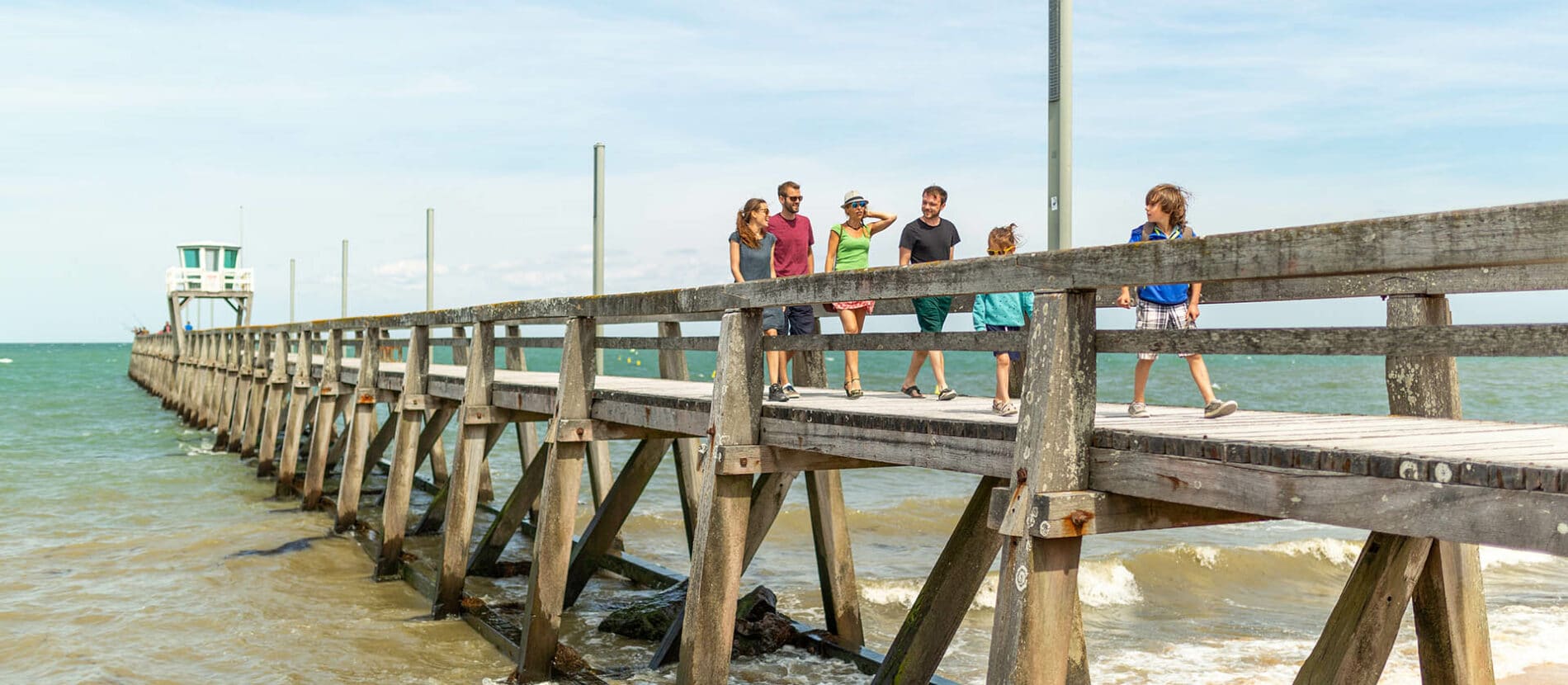 Une famille en balade sur le ponton au dessus de la mer à Luc-sur-mer