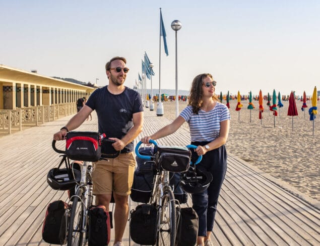 Couple en balade à vélo sur les planches de Deauville