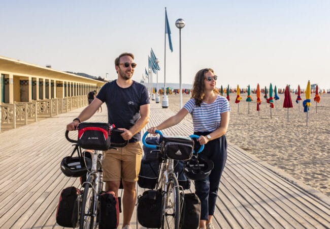 Couple en balade à vélo sur les planches de Deauville