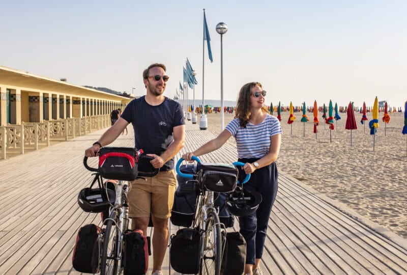 Couple en balade à vélo sur les planches de Deauville