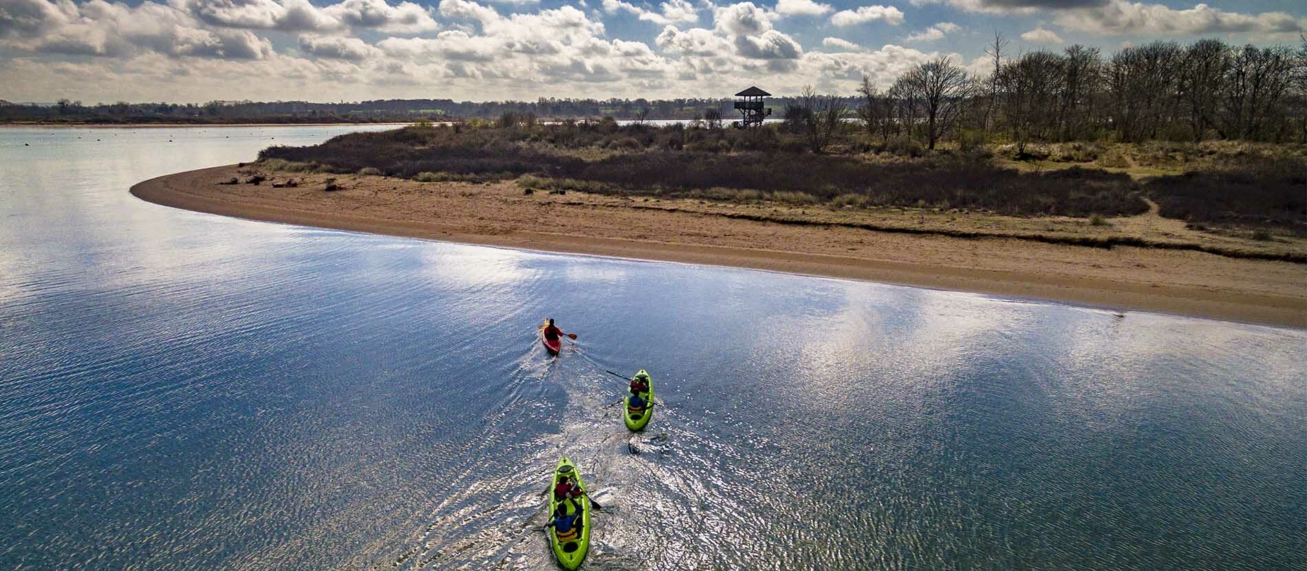 Kayaks bi-places et simple en train de naviguer dans la Baie de l'Orne avec vue sur l'observatoire de la Pointe du Siège