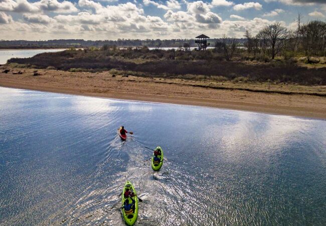 Kayaks bi-places et simple en train de naviguer dans la Baie de l'Orne avec vue sur l'observatoire de la Pointe du Siège